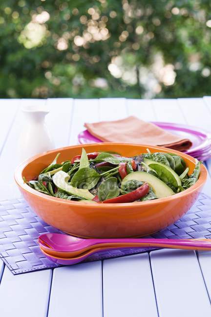 Spinatsalat mit gebratenem Gemüse und Avocado im Orangenteller — Stockfoto