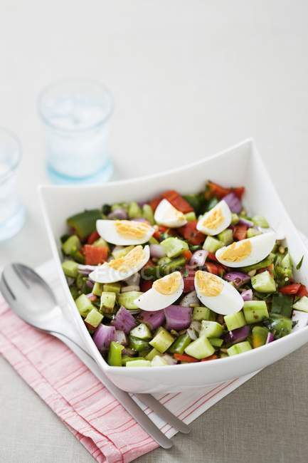 Vista de cerca de ensalada de verduras con huevos en tazón cuadrado - foto de stock