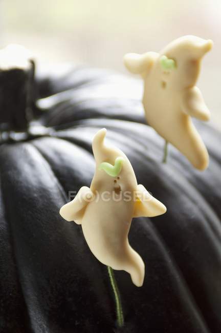 Fantasmi di caramelle in una zucca nera — Foto stock