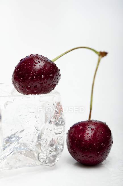 Red cherries with ice cube — Stock Photo