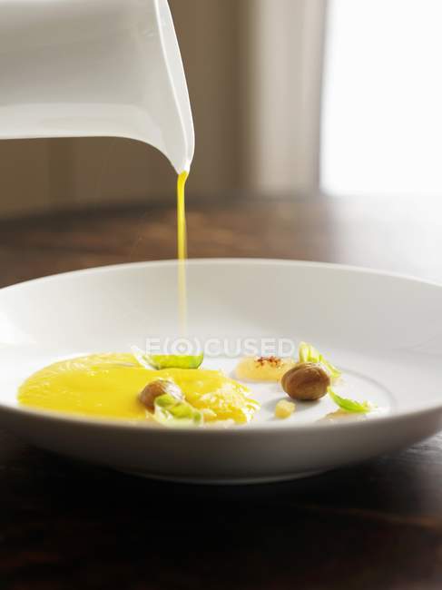 Pouring Smooth and Creamy Squash Soup into a White Bowl with Garnishes — Stock Photo