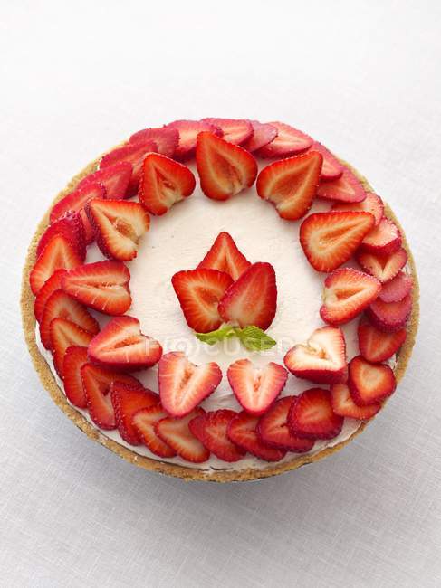 Gâteau garni de fraises fraîches tranchées — Photo de stock