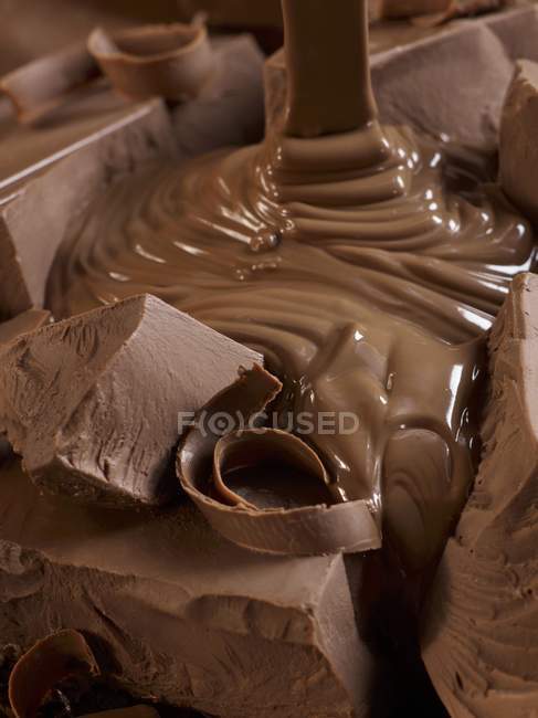 Chocolate derretido vertiendo sobre trozos - foto de stock
