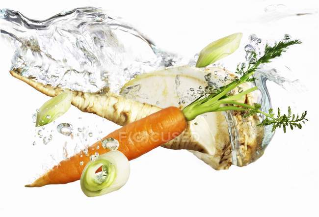 Soup vegetables falling into water  on White background — Stock Photo