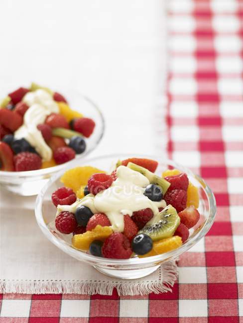 Summer fruit salad with cream in glass bowls over towel — Stock Photo