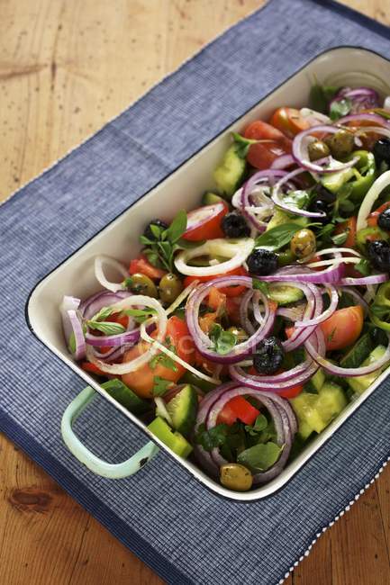 Ensalada mediterránea de verduras con tomates, pepino, aceitunas y cebollas en plato - foto de stock