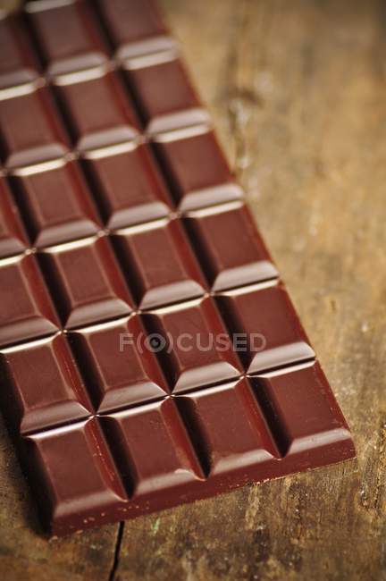 Barre de chocolat sur table en bois — Photo de stock