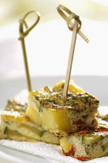 Spanish tortilla; made of eggs, potatoes, zucchini, garlic, chillies and fresh mint - cut and put on sticks — Stock Photo
