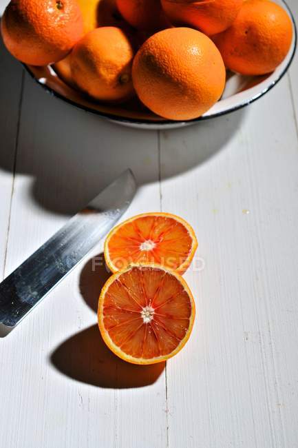 Кровь апельсинов в миске с половинками — стоковое фото