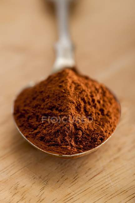 Vista de cerca del cacao en polvo en cuchara y superficie de madera - foto de stock