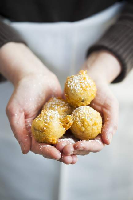 Cropped view of hands holding Beignets sprinkled with powdered sugar — Stock Photo