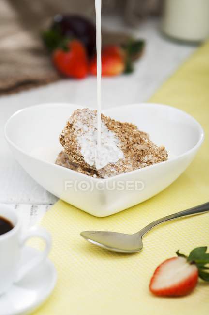 Milk being poured onto wheat cereal — Stock Photo