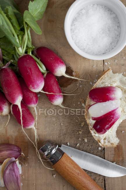Fresh radishes with slices on bread — Stock Photo