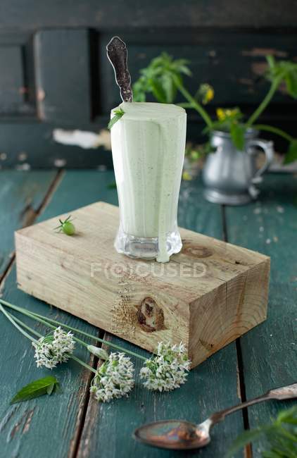 Mint yogurt sauce in a glass with a spoon on a wooden block — Stock Photo