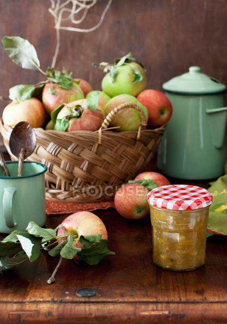 Closeup view of yellow tomato and apple Chutney on a table with a basket of fresh apples — Stock Photo