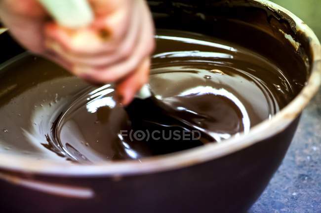 Руки, перемешивающие расплавленный шоколад — стоковое фото