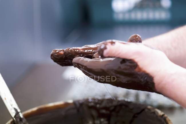 Крупный план обрезанный вид рук катящихся трюфелей в расплавленном шоколаде — стоковое фото