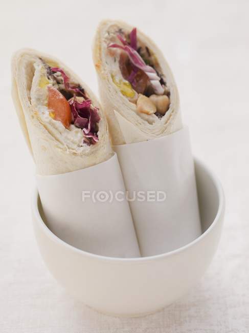 Wraps filled with houmous and tomatoes in white pot — Stock Photo