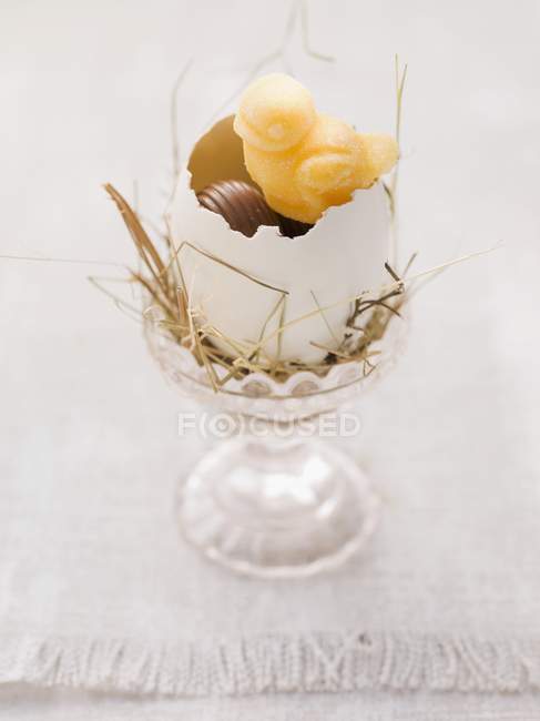 Vista de primer plano del nido de Pascua en taza de huevo y dulces - foto de stock
