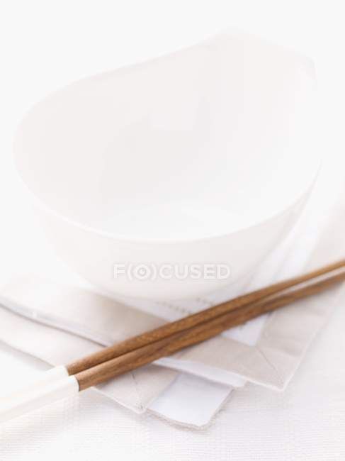 Крупный план сервировки стола с чашей и палочками на белой салфетке — стоковое фото