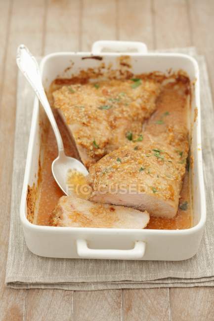 Baked turkey breast with sesame and carrot topping in white dish with spoon — Stock Photo