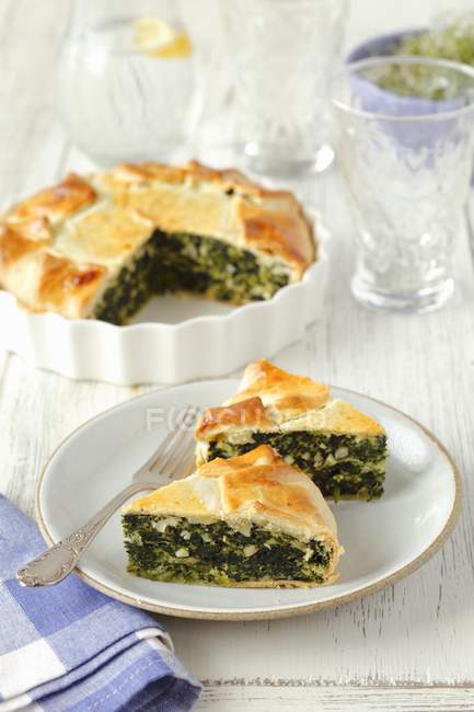 Spinach pie with almonds in white plate with fork — Stock Photo