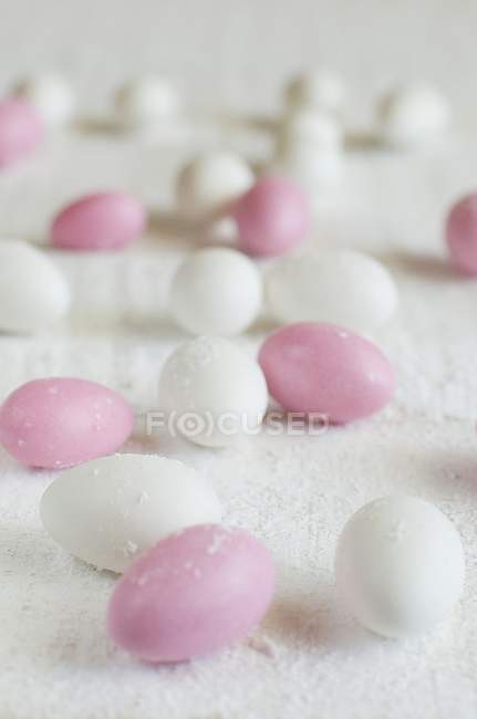 Vista de cerca de los huevos blancos y rosados de azúcar dispersos - foto de stock