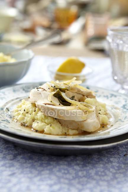 Poached chicken breast with lemon and tarragon  on plates over table — Stock Photo