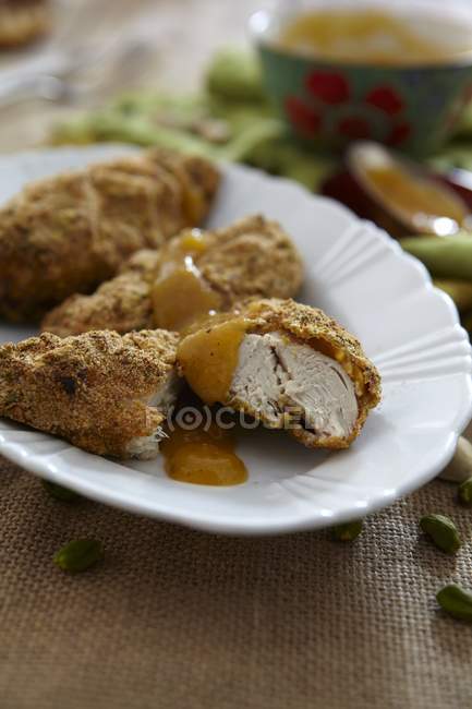 Крупный план куриной грудки с фисташковой коркой и абрикосовым соусом — стоковое фото