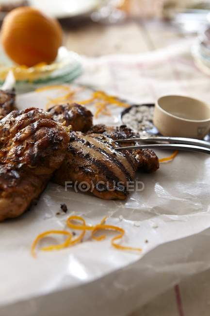 Barbecued chicken with garlic, fennel and oranges on baking paper with fork — Stock Photo