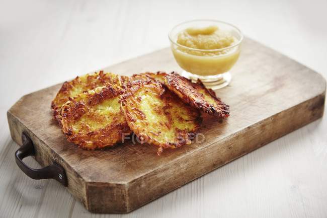 Potato rstis with apple puree on wooden chopping board over wooden surface — Stock Photo