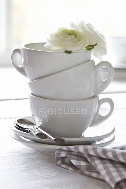 Vue rapprochée de tasses empilées décorées de fleurs blanches — Photo de stock