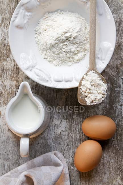 Vista superior de los huevos con leche y harina - foto de stock