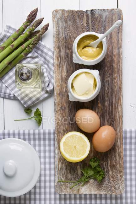 Ingredients for sauces served with asparagus over wooden desk on table — Stock Photo