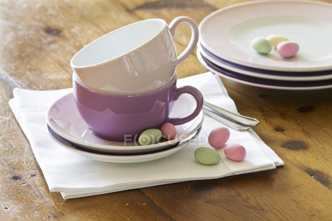 Gestapelte Teller und Tassen mit pastellfarbenen Zuckereiern — Stockfoto