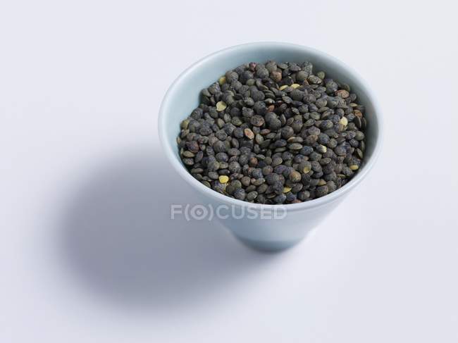 Closeup view of black lentils in a white bowl — Stock Photo