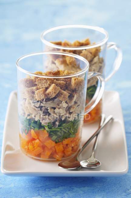 A layered starter with croutons and smoked mackerel in glases on white plate — Stock Photo