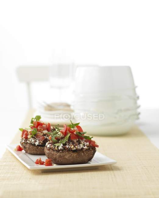Champiñones rellenos con tomates y cohete en placa sobre superficie de madera - foto de stock