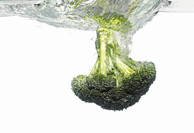 Brócolos caindo na água — Fotografia de Stock