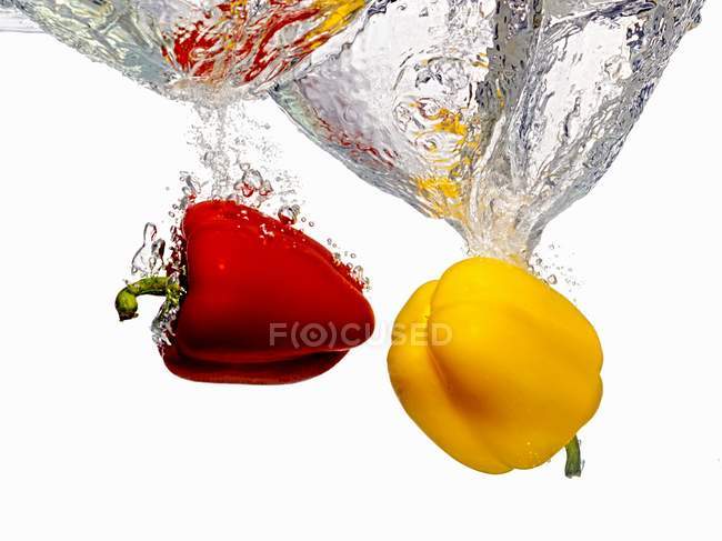 Peppers Splashing into Water — Stock Photo