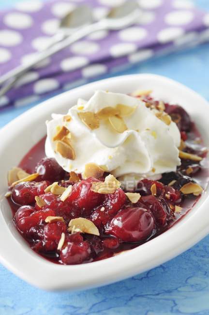 Closeup view of stewed cranberries topped with creamy coconut and slivered almonds — Stock Photo