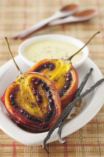 Baked tamarillos with vanilla sauce  on white plate over table — Stock Photo