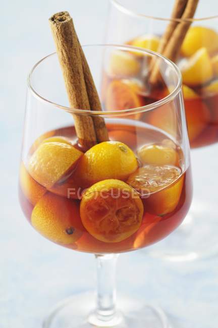 Vista de cerca de kumquats en vino con palos de canela - foto de stock