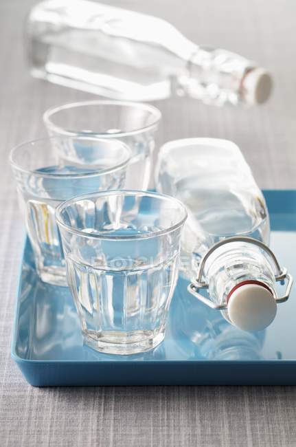 Vista da vicino di tre bicchieri e due bottiglie d'acqua — Foto stock