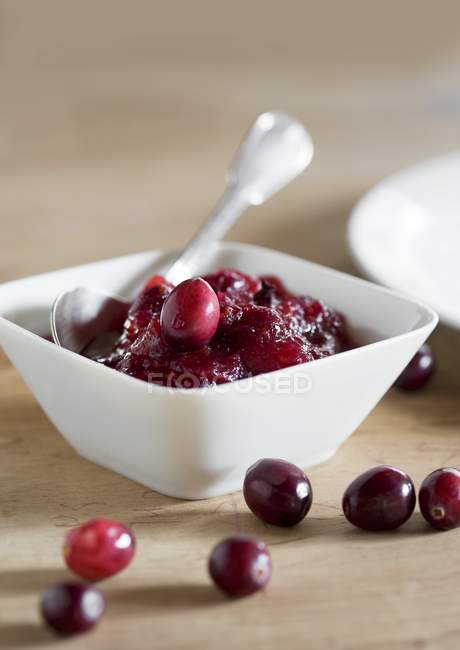 Closeup view of cranberry sauce with spoon in bowl — Stock Photo