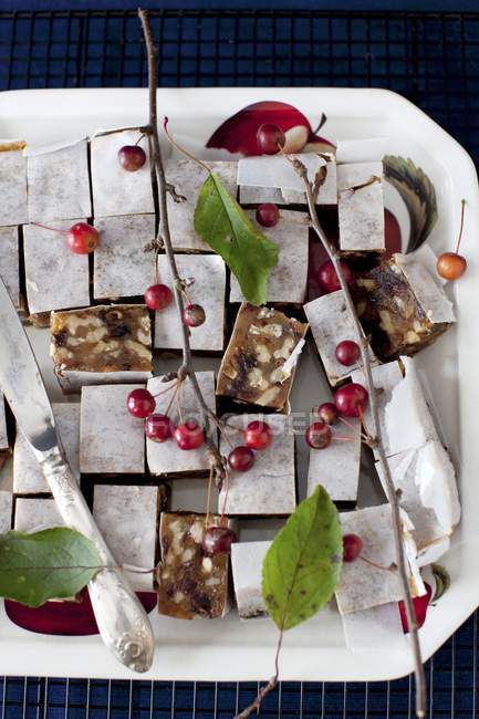 Top view of Panforte squares on a platter with berries and a knife — Stock Photo
