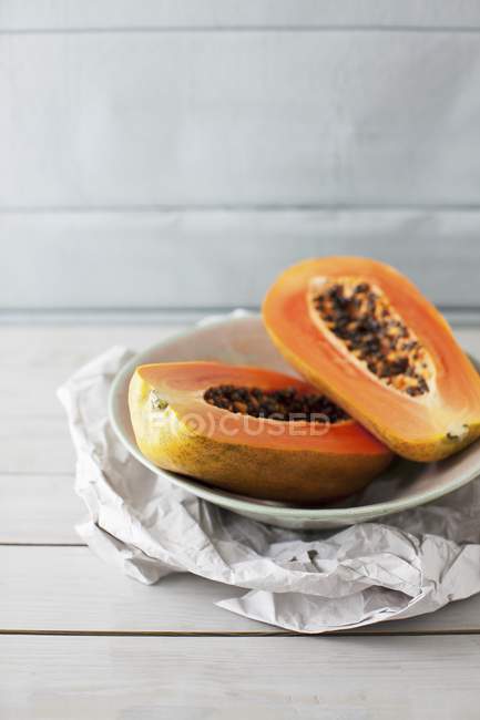 Papaya dimezzata in ciotola su carta — Foto stock