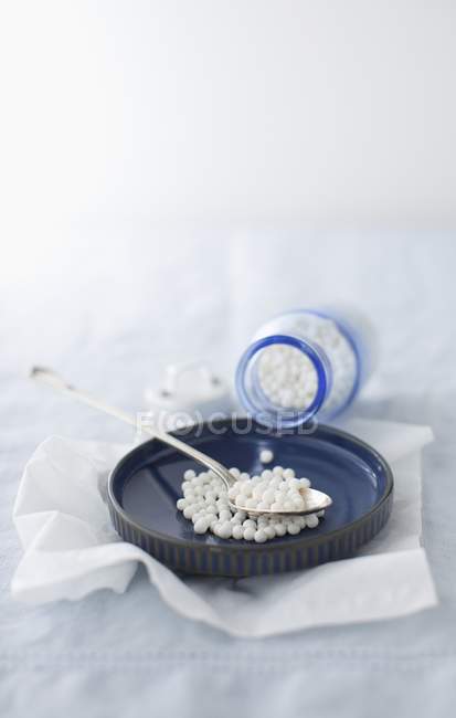 Tapioca Pearls Spilling from a Bottle into a Shallow Bowl with a Spoon — Stock Photo