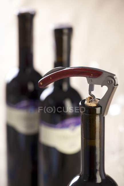 Vista close-up de garrafa de vinho tinto com saca-rolhas — Fotografia de Stock