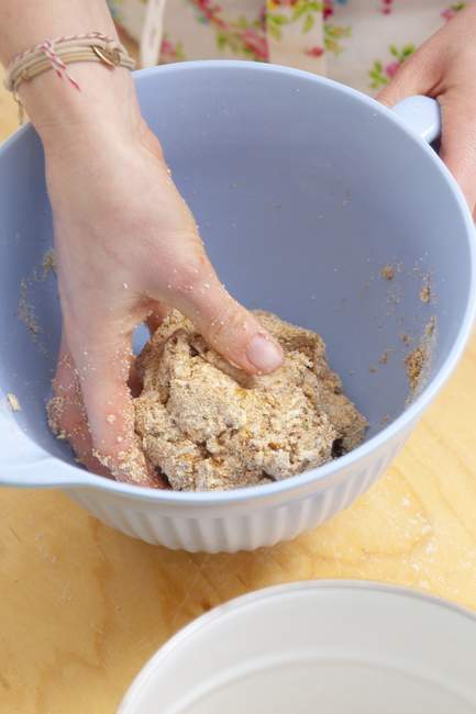 Closeup view of hand kneading biscuit dough in a bowl — Stock Photo